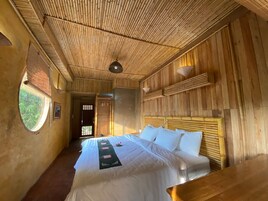 Quarto com uma cama grande, teto de madeira e uma janela.