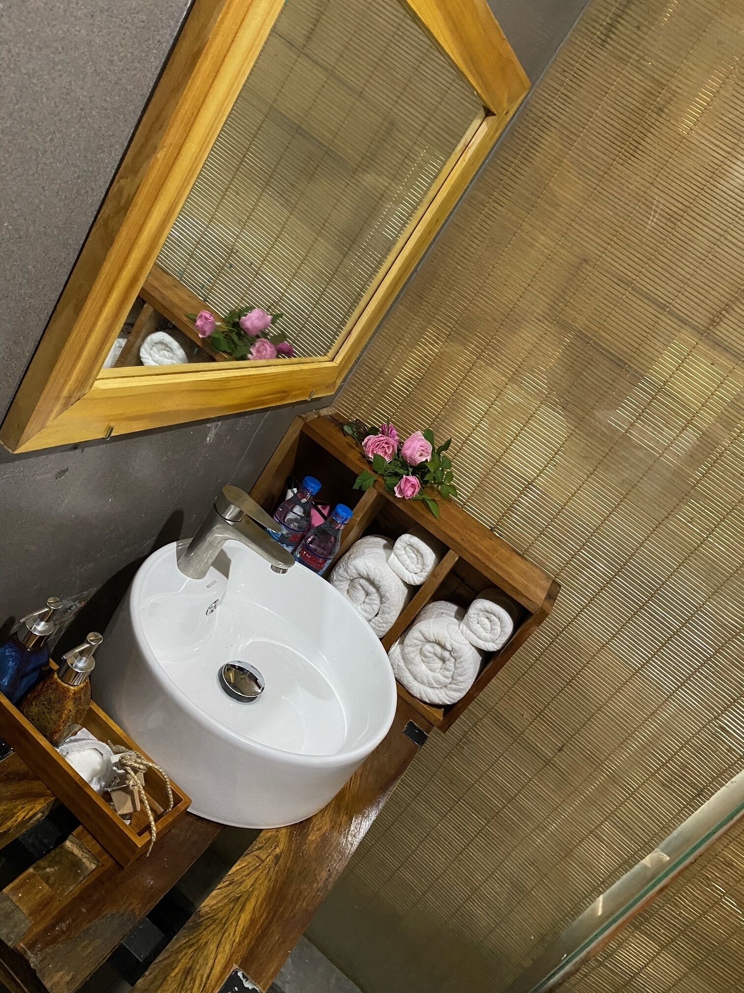 A bathroom with a white sink, a wooden vanity, a mirror, and a towel rack with neatly folded towels.