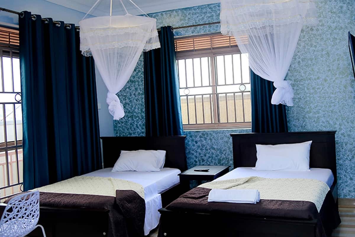 Une chambre d’hôtel avec deux lits, une petite table, une chaise et un téléviseur fixé au mur.