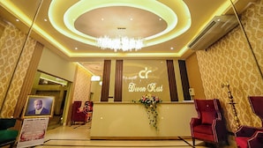 A reception area with a chandelier, a reception desk, and red upholstered chairs. - Devon Rest (Kandy)
