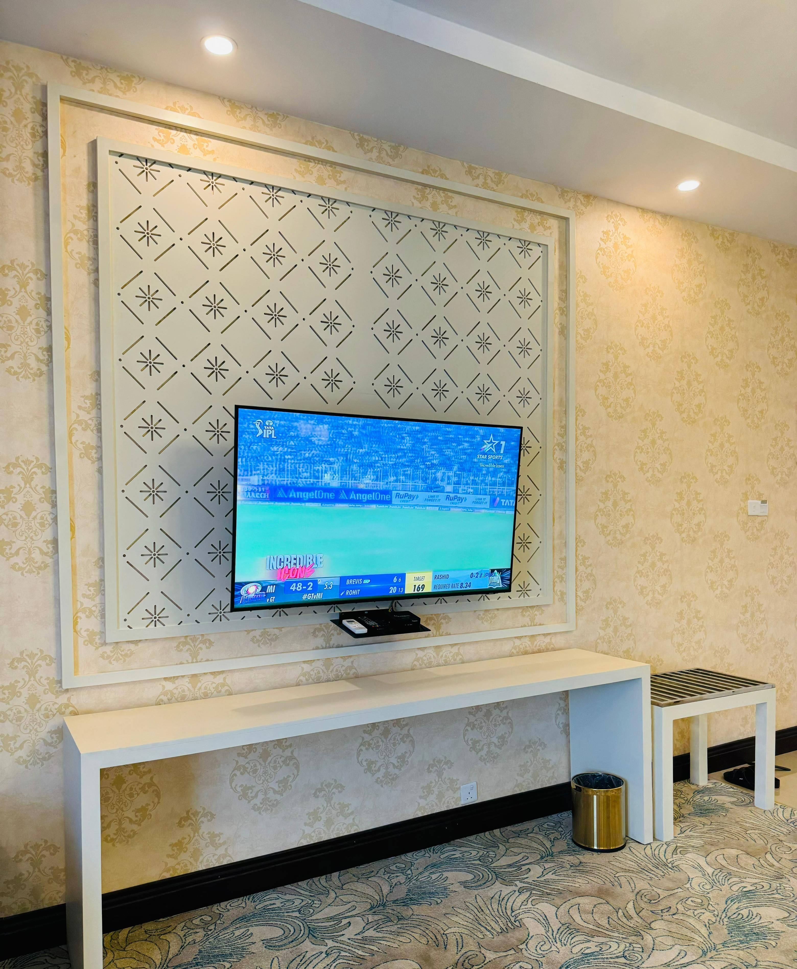A television mounted on a wall with a patterned backdrop.