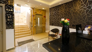 A reception area with a glass door leading to a staircase, a black reception desk with a vase of flowers, and a laptop on the desk. - Venus Pyramids Inn (Giza)