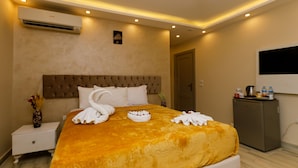 A hotel room with a large bed, a nightstand, an air conditioning unit, a small refrigerator, and a flat-screen TV on the wall. - Venus Pyramids Inn (Giza)