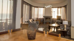 A modern living room with a fireplace, comfortable seating, and large windows.