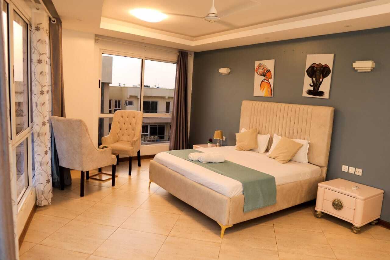 Un dormitorio con una cama grande, una silla, una mesita de noche y una ventana con cortinas.