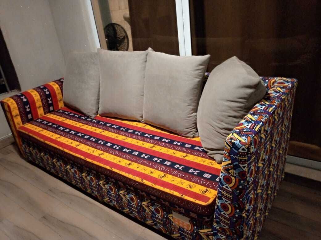 Ein Sofa mit farbig gemustertem Bezug und beigen Kissen.