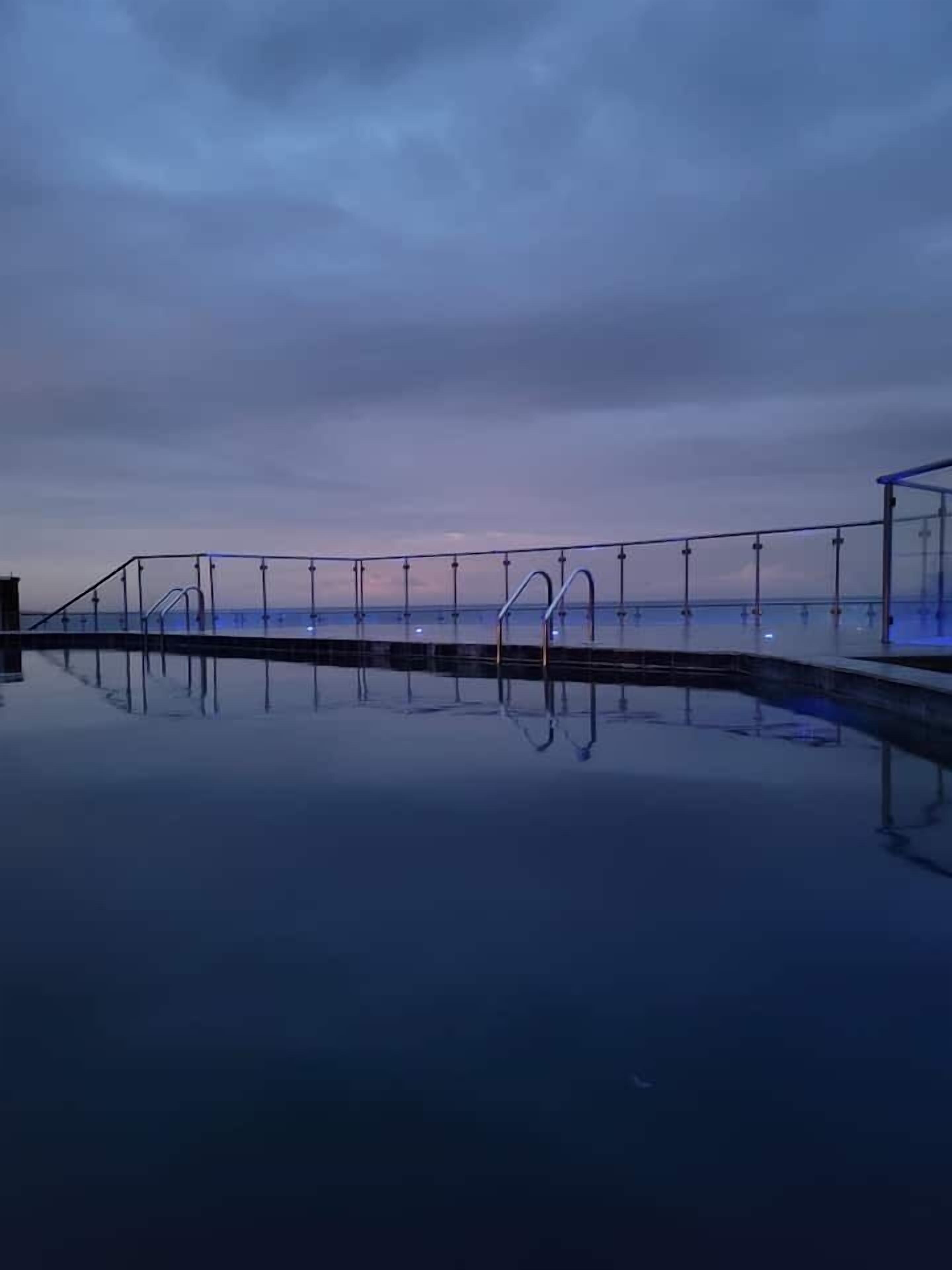 Ein Pool mit Glasgeländer, das den Himmel spiegelt.