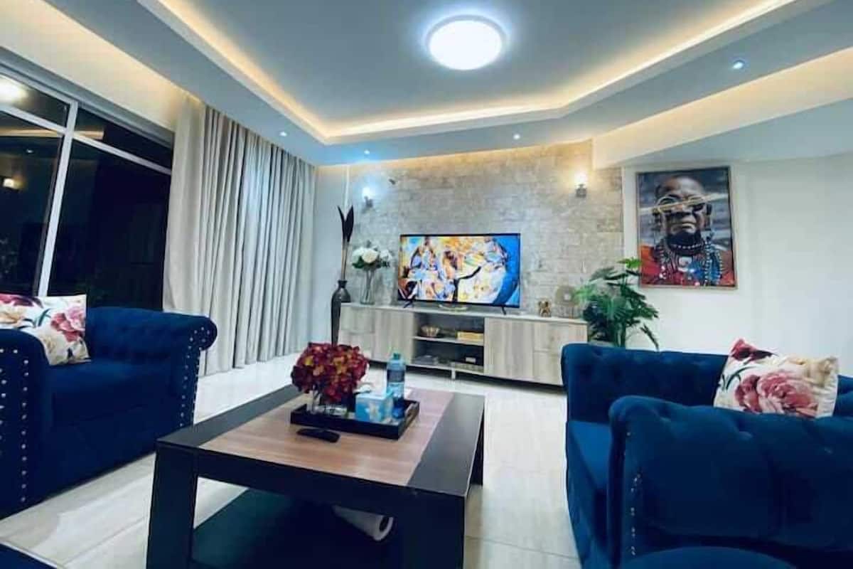 Ein modernes Wohnzimmer mit zwei blauen Sofas, einem Couchtisch, einem Flachbildfernseher und einer Wand mit Steinverkleidung.