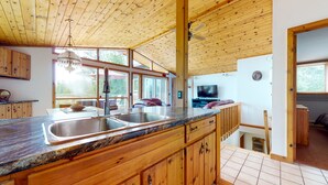 A kitchen with wooden cabinets, a granite countertop, a stainless steel sink, and a ceiling fan.