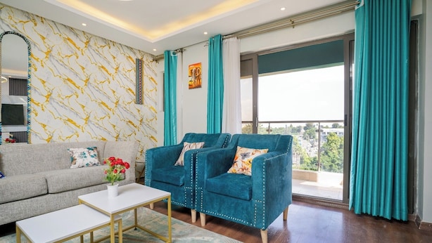A living room with a grey sofa, a teal armchair, a white coffee table, and a patterned rug.