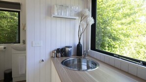 A modern kitchen with a large window, white cabinetry, and a stainless steel sink.