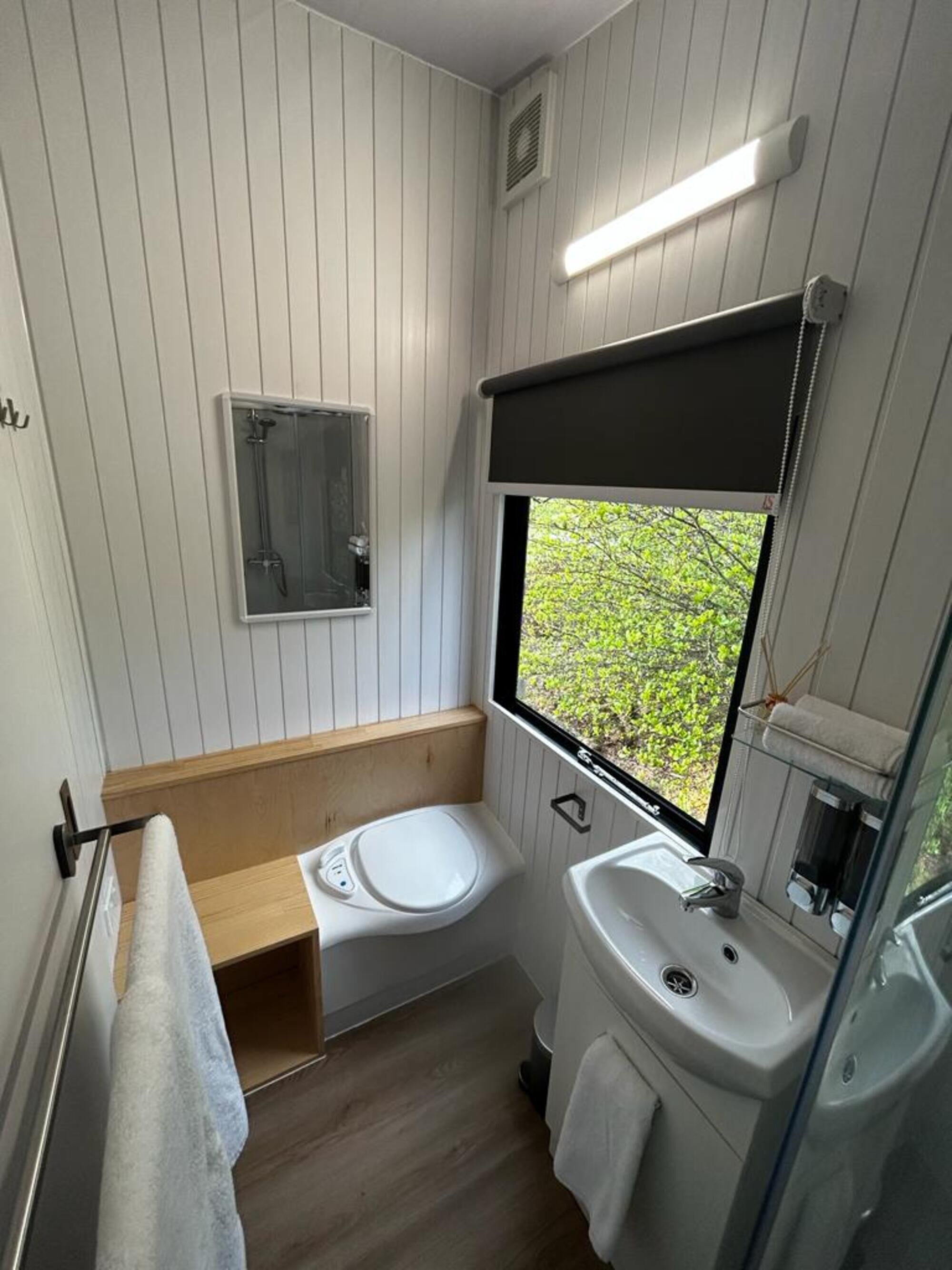 A compact bathroom with a window, a shower, and a sink.