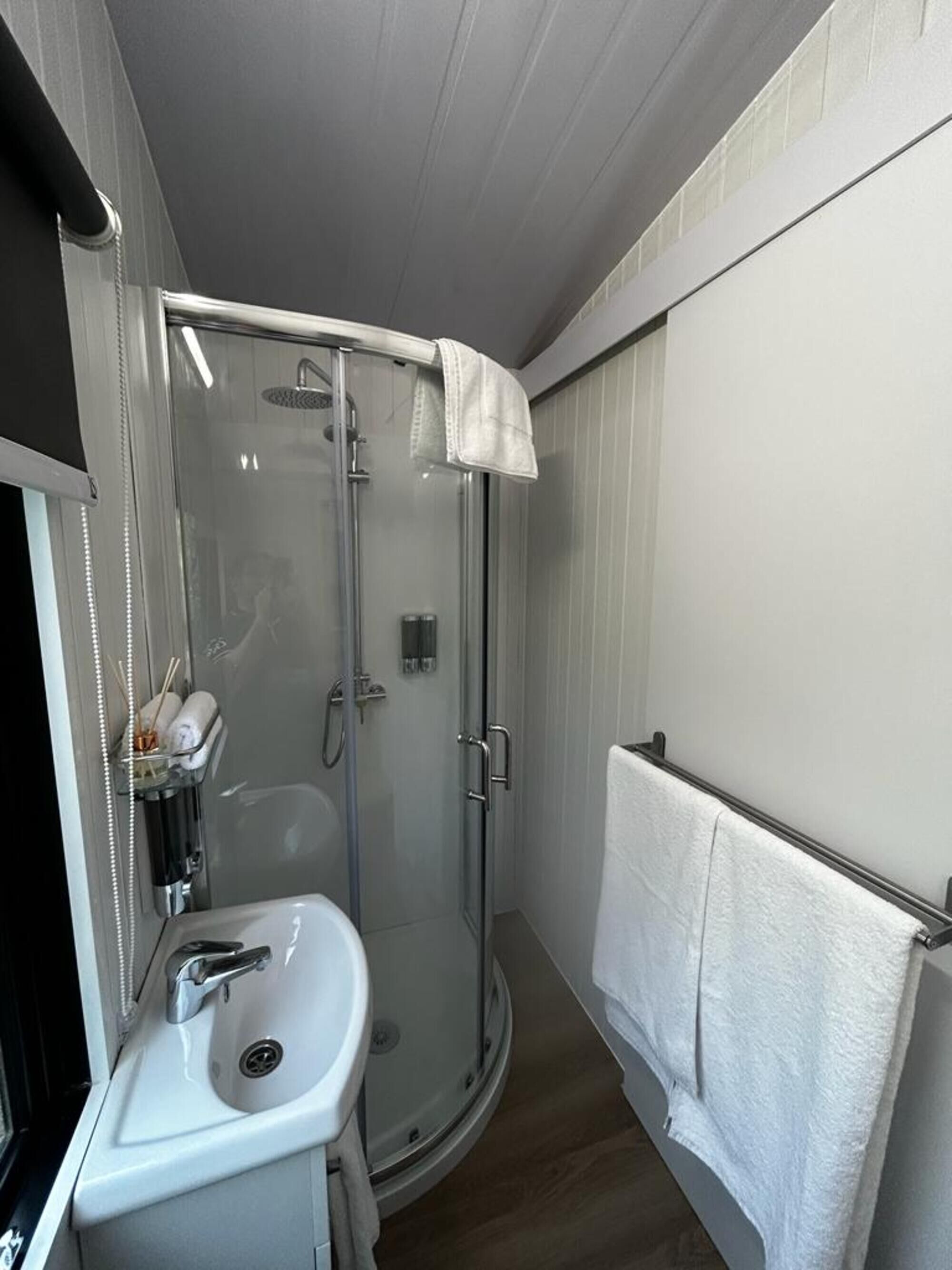 A modern bathroom with a glass-enclosed shower, a white sink, and a towel rack.