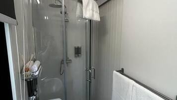 A modern bathroom with a glass-enclosed shower, a white sink, and a towel rack.