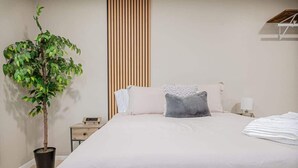 Ein Schlafzimmer mit Bett, Nachttisch, Blumentopf und einer Holzwand.