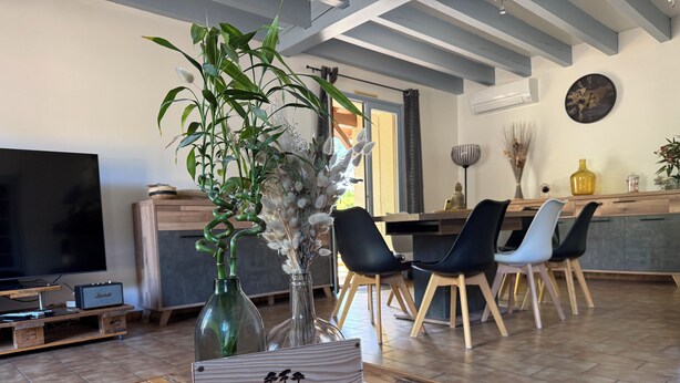A modern living room with a TV, wooden coffee table, and a dining area with chairs and a kitchen in the background. - Villa du Raz 2, Traditionnelle et Familiale à 40 Mètre de la Piste Cyclable (Mimizan)