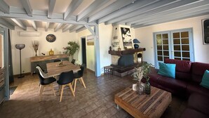 A spacious living area with a wooden dining table, black chairs, a red sofa, and a fireplace. - Villa du Raz 2, Traditionnelle et Familiale à 40 Mètre de la Piste Cyclable (Mimizan)