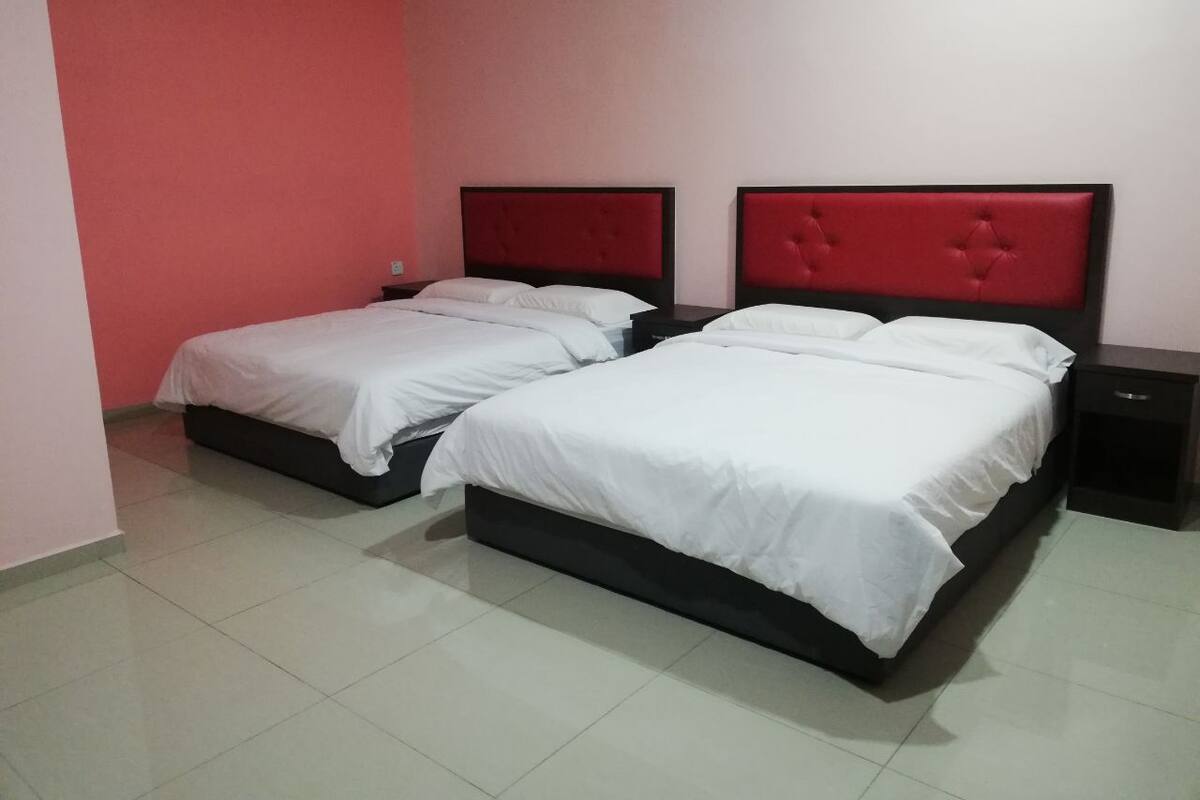 Habitación de hotel con dos camas, cada una con cabecero rojo y ropa de cama blanca.