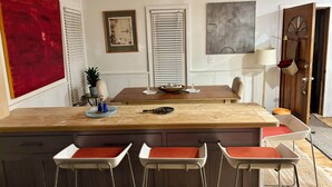 A kitchen with a central island, bar stools, a dining table, and a large abstract painting. - Score The perfect Summer Winter getaway: Lakeside retreat for your winning team  (Maryland)