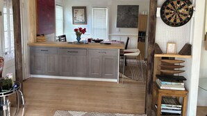 A kitchen with a central island, grey cabinets, a dartboard, and a bookshelf with books. - Score The perfect Summer Winter getaway: Lakeside retreat for your winning team  (Maryland)