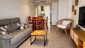 Un salon moderne comprenant un canapé, une table basse, une table à manger, des chaises et un fauteuil en osier.