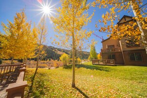 A wooden deck with benches, a building with a balcony, and a clear sky. - Red Hawk Townhomes 2345 (Keystone)