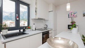 Uma cozinha moderna com uma janela grande, armários brancos, uma pia de aço inoxidável e uma tigela grande no balcão.