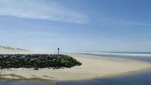 Une plage avec une digue rocheuse et un ciel dégagé.