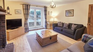 A living room with a television, sofa, and a wooden chest of drawers. - Church Cottage Beadnell  (Beadnell)