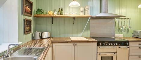 Een keuken met een inbouwoven, een spoelbak en een houten aanrecht.