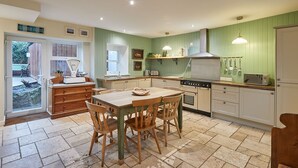A kitchen with a dining table, chairs, a stove, and a sink. - Church Cottage Beadnell  (Beadnell)