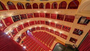 Et teater med flere niveauer, røde sæder og udsmykket arkitektur.