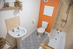 Bathroom features a pedestal sink, toilet, and bathtub with showerhead.