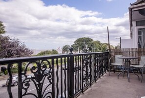 Enjoy the view from this balcony with a wrought iron railing, featuring two comfortable chairs and a small table.