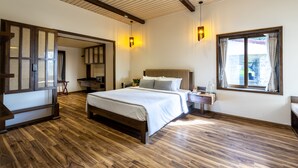 A spacious bedroom with a large bed, wooden flooring, a built-in wardrobe, and a window with curtains.