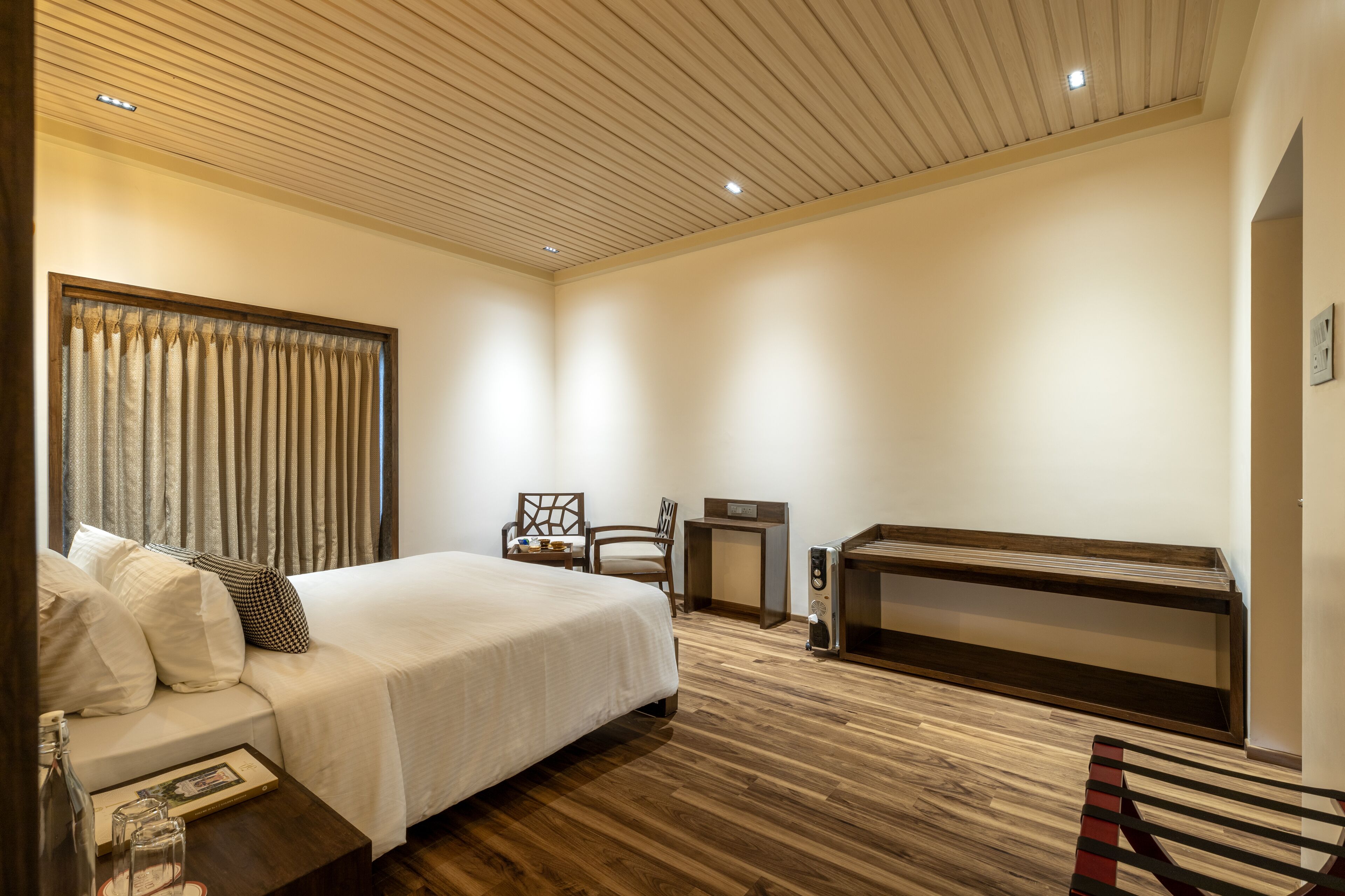 Una habitación de hotel moderna con una cama grande, un escritorio, una silla y un banco.