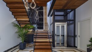 Un intérieur moderne avec un escalier en bois, un sol à motifs géométriques et une plante en pot.