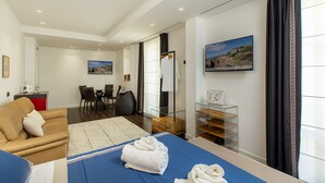 Une chambre d’hôtel moderne comprenant un lit, un canapé, un coin repas et une cloison en verre.
