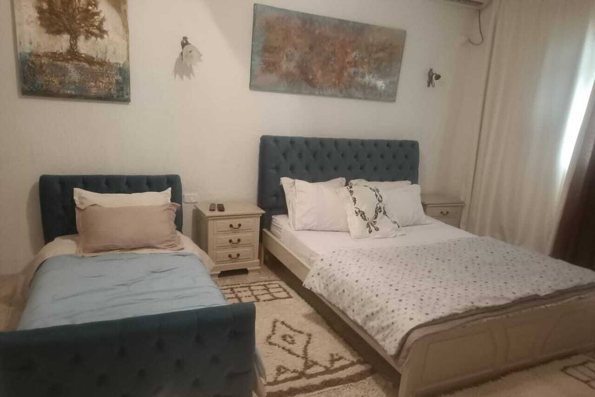 Ein Schlafzimmer mit zwei Betten, einem Nachttisch, einer Kommode und Bildern an der Wand.