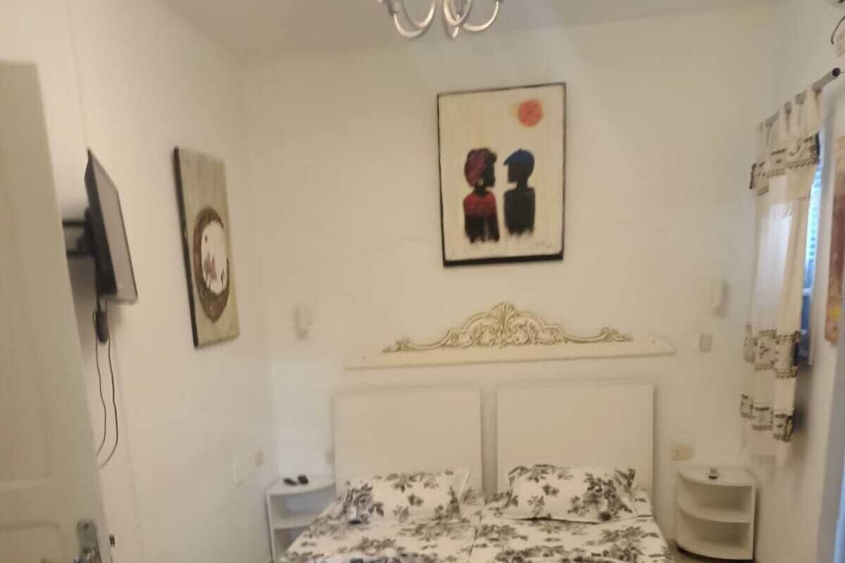 Ein Schlafzimmer mit einem Bett, einem runden Tisch, einem Teppich, einem Spiegel und einem an der Wand befestigten Fernseher.
