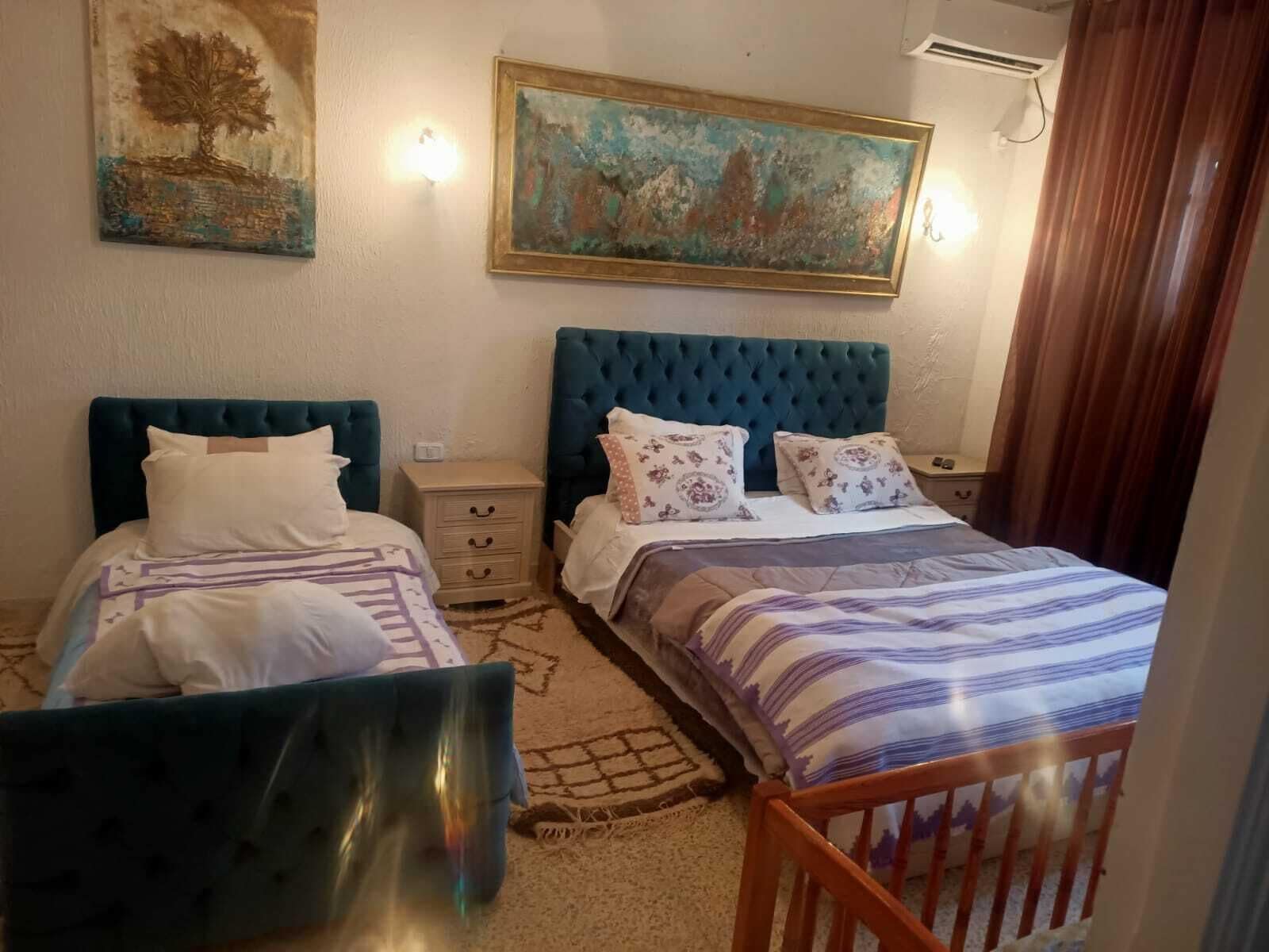A bedroom with two beds, a nightstand, a dresser, and a painting on the wall.