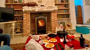 Una sala de estar con chimenea de ladrillo, estanterías y un comedor con comida y bebidas.
