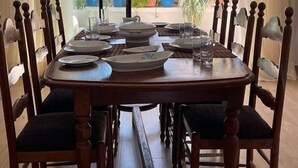 Comedor con una mesa dispuesta para seis personas, rodeada de sillas de madera con asientos acolchados.