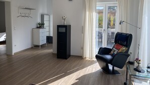 Una sala moderna con un sillón de cuero negro, una mesa de centro de vidrio y un mueble blanco.
