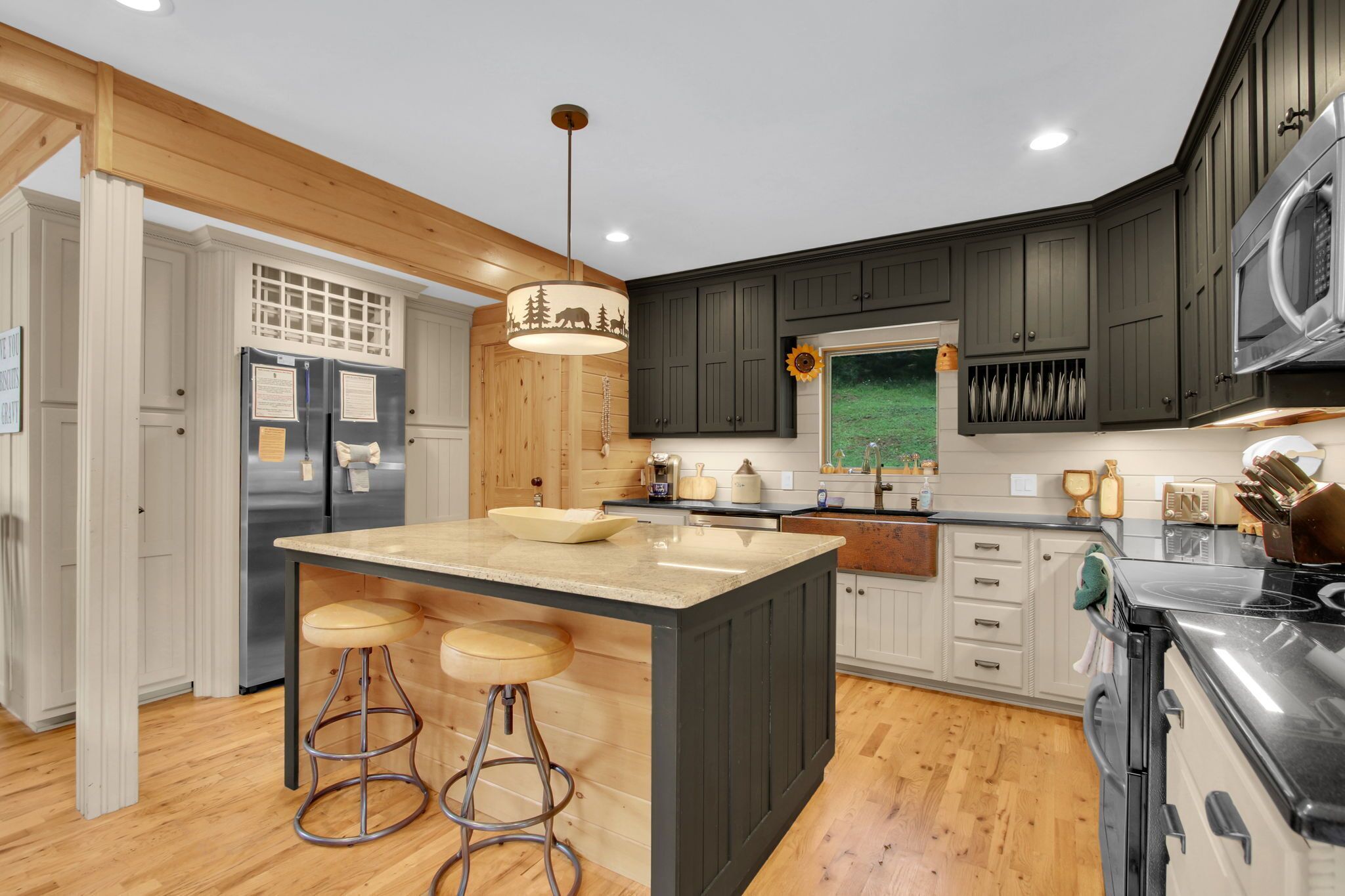A modern kitchen with a central island, bar stools, wooden cabinetry, and a built-in oven.