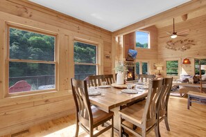 Un interior de madera con una mesa de comedor preparada para cuatro personas, rodeada de sillas.
