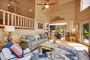 A spacious wooden interior with a sofa, coffee table, and a dining area.