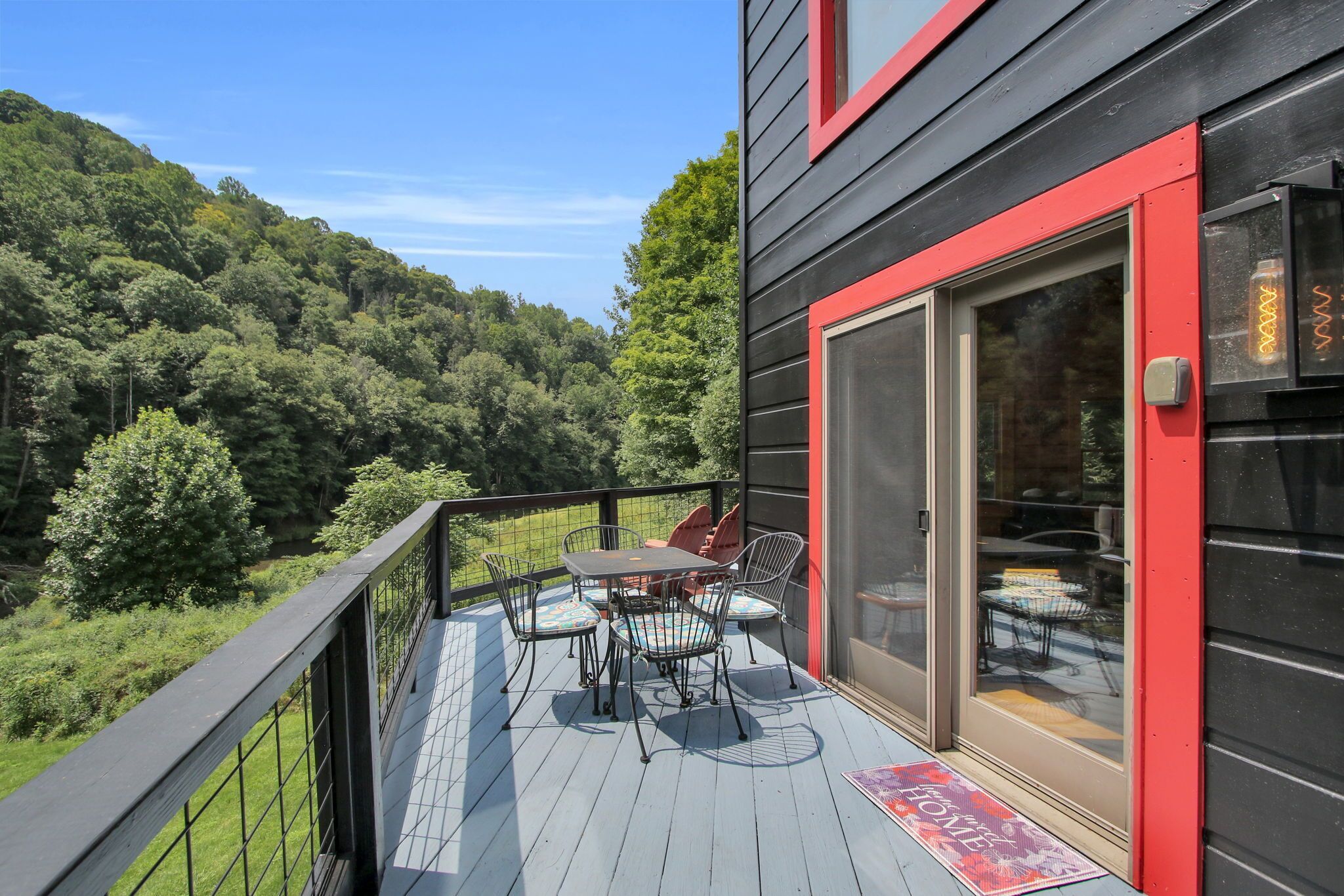 Terraza con mesa y sillas, con vista a un paisaje boscoso.