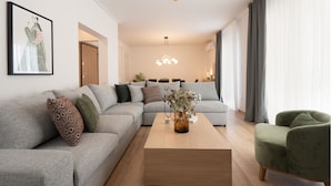 Un salón moderno con un sofá seccional gris, una mesa de centro de madera y un sillón verde.