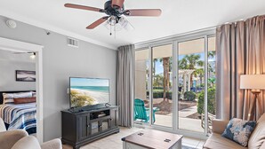 A hotel room with a large sliding glass door to the outdoors, a ceiling fan, a flat-screen TV, a sofa, and a coffee table. - Waterscape 1 bedroom w bunks A side walkout -beach (Ft Walton Beach)